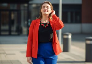 Mladá plus size žena stojaca vonku v modernom outfite s mestským pozadím a prirodzeným svetlom