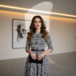Žena v čierno-bielych šatách s minimalistickými doplnkami v modernom interiéri.